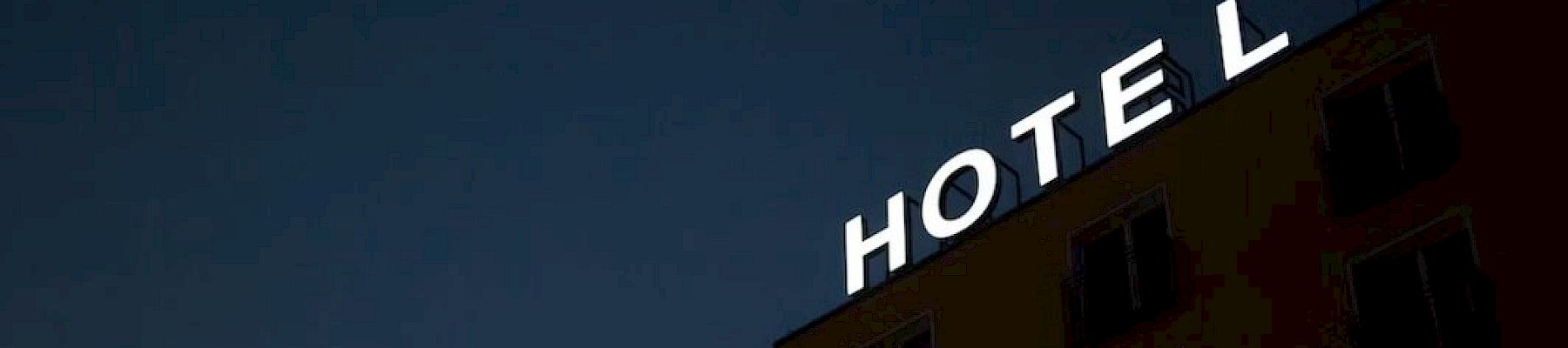 A building with a glowing HOTEL sign against a dark blue night sky, with windows below.